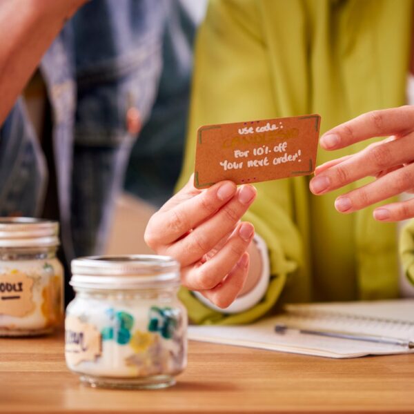 Couple Running Online Business Making Boutique Candles At Home Writing Discount Voucher